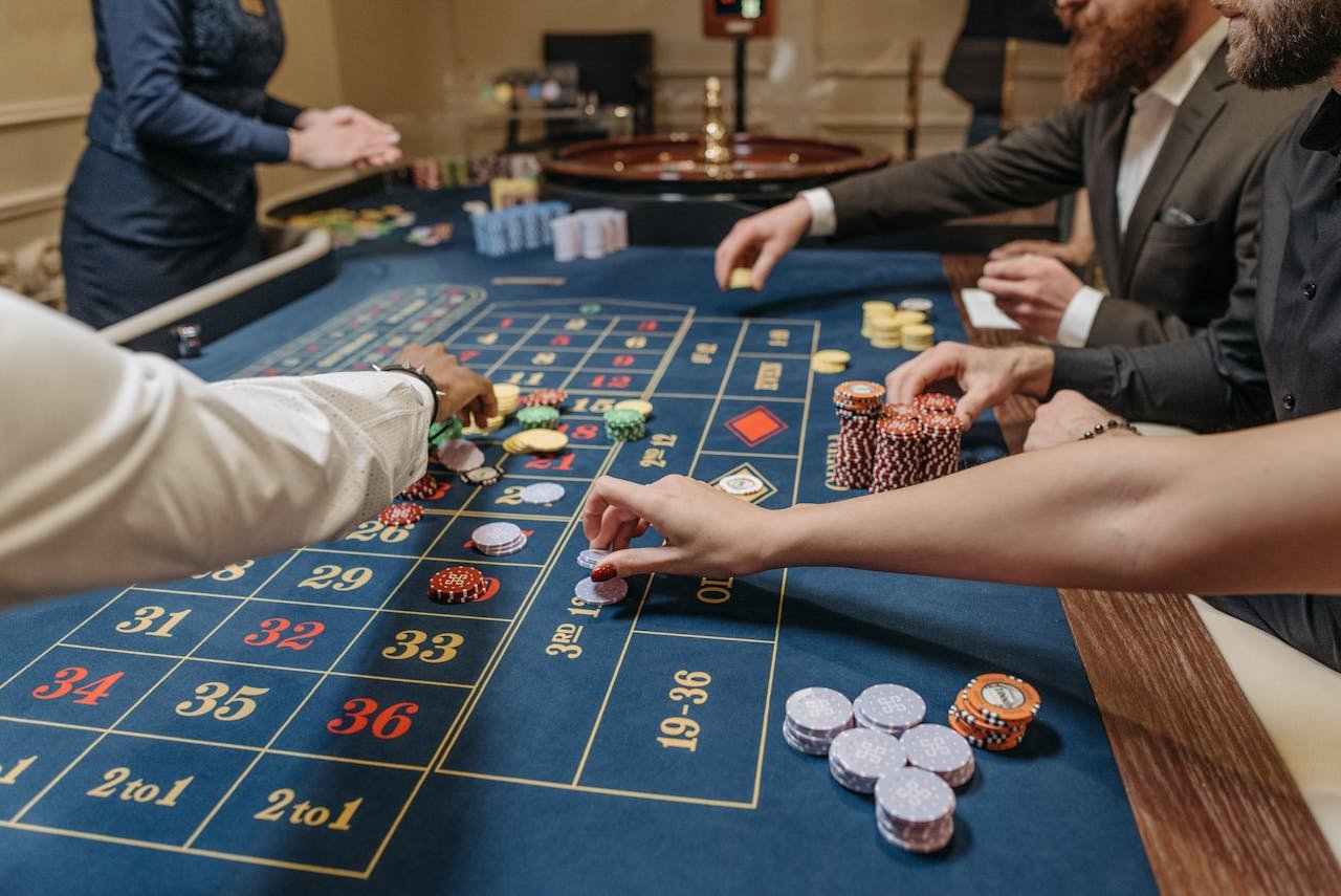 A lively casino scene with players placing bets and handling gaming chips on a roulette table.