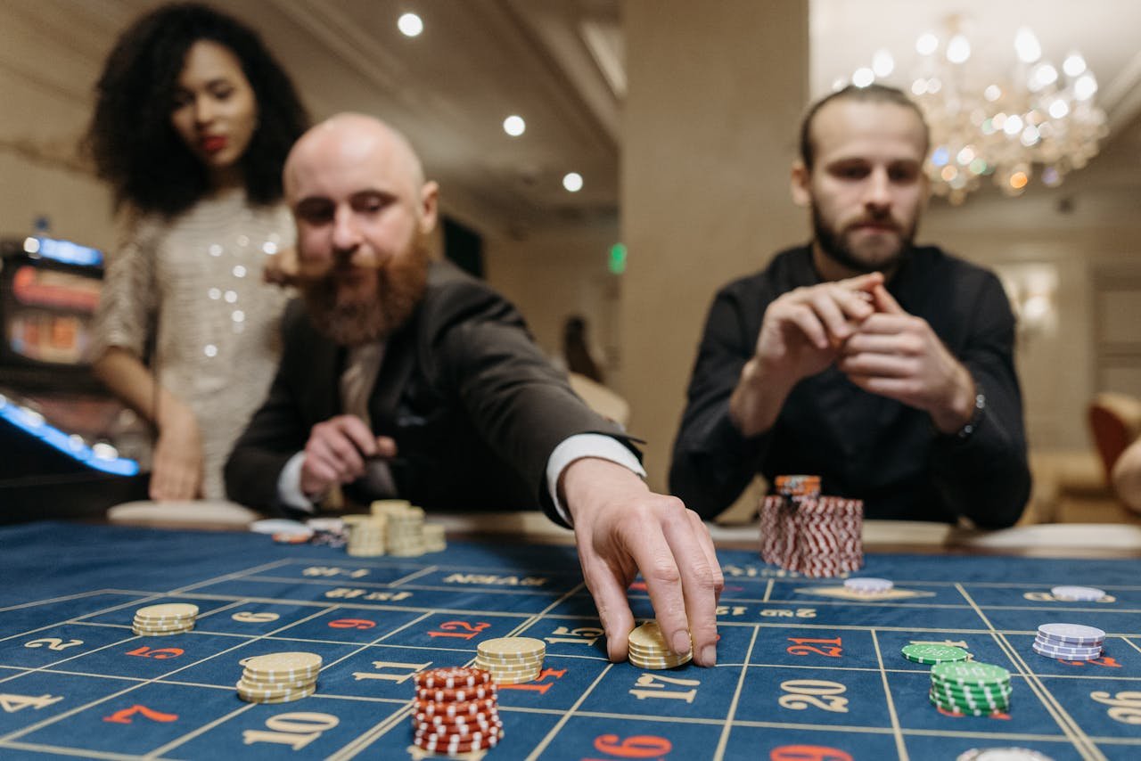 discover Three adults playing roulette at a casino, focused on placing bets with gaming chips.